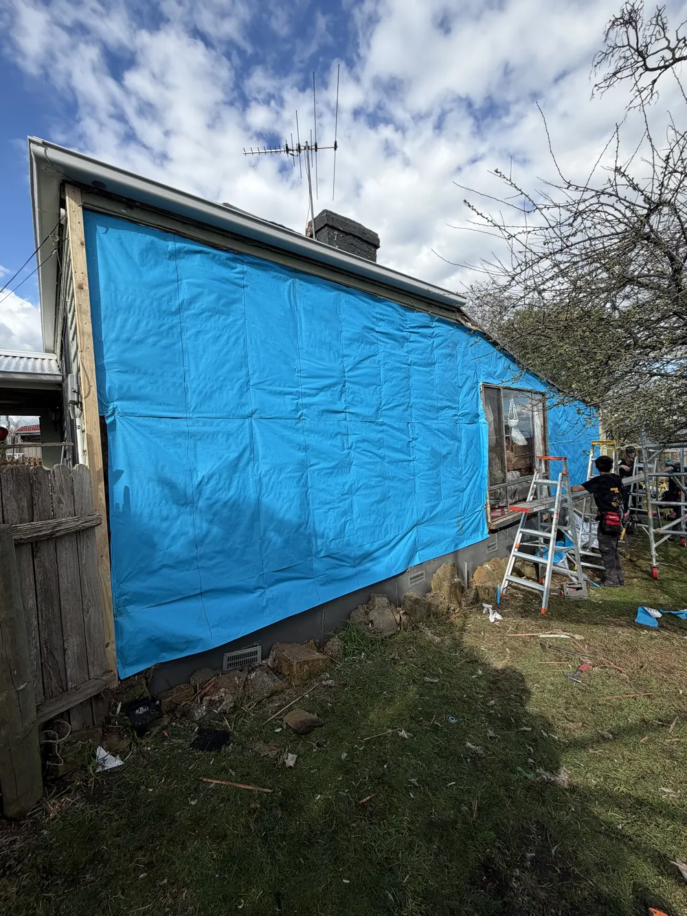 Exterior wall covered with blue building wrap during recladding