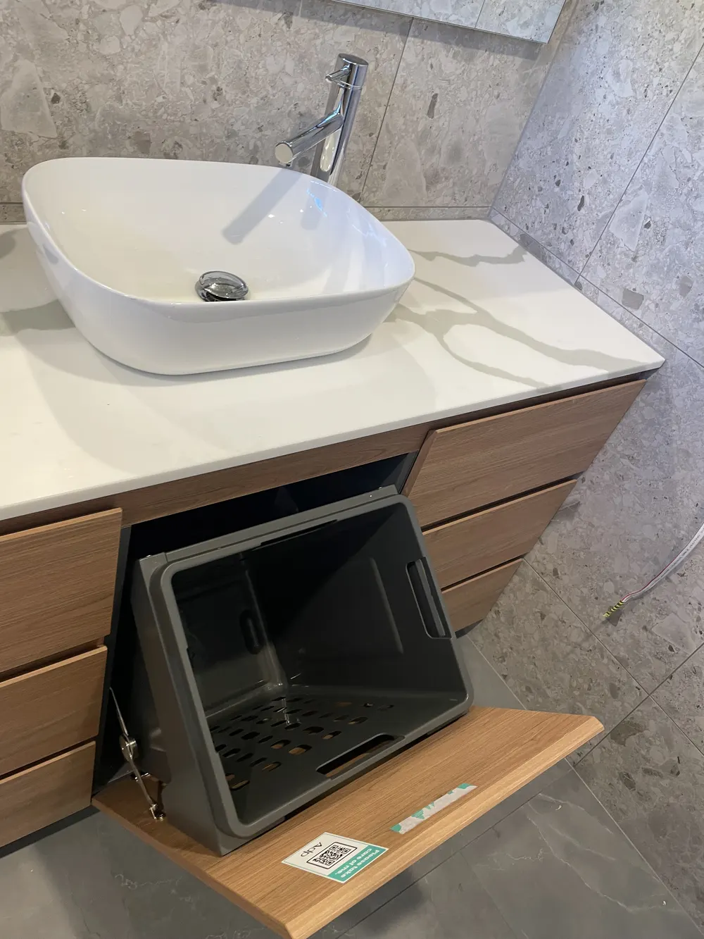 Open drawer in a timber bathroom vanity below a white vessel basin