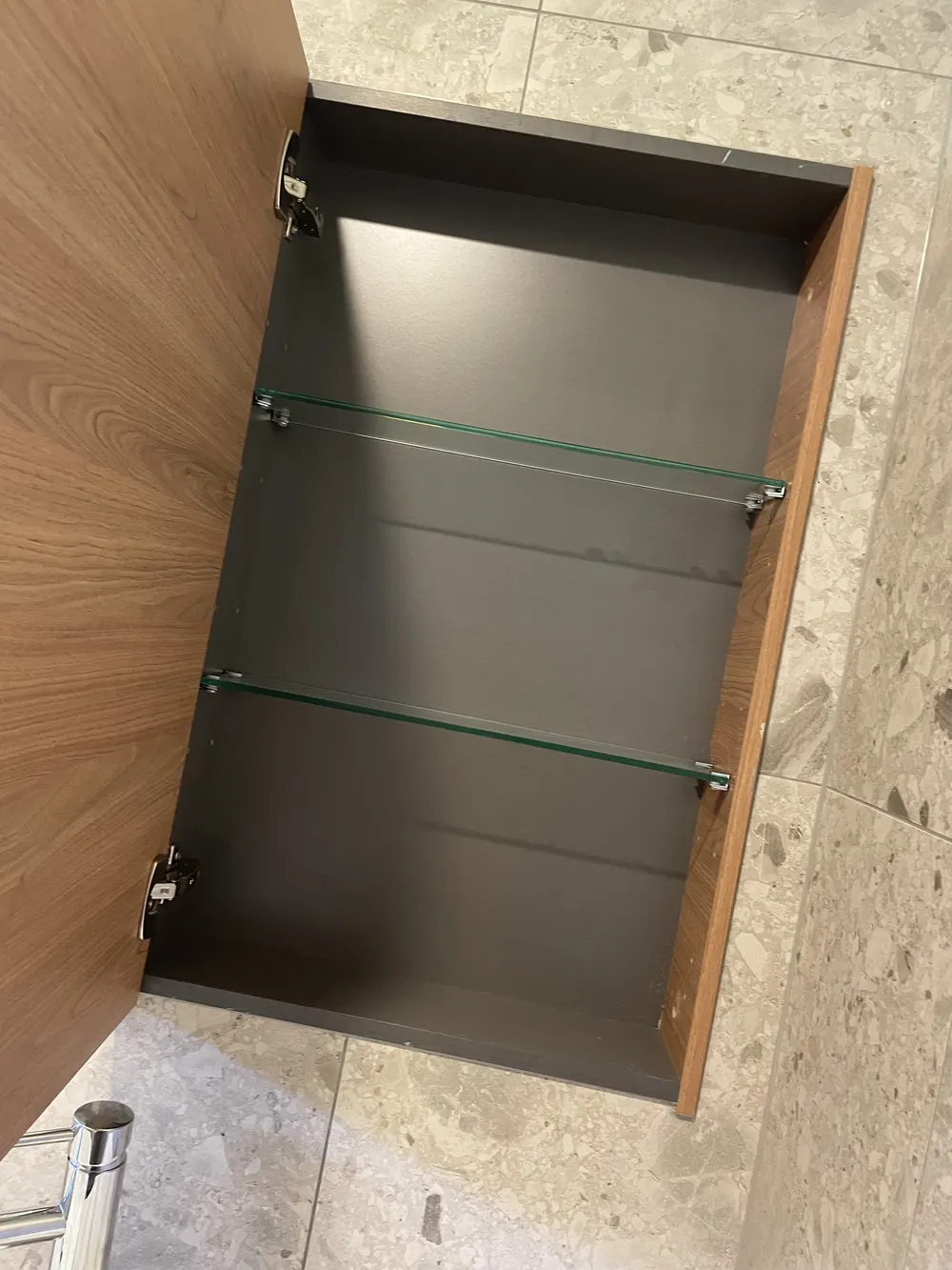 Recessed bathroom cabinet with glass shelves and a mirrored door