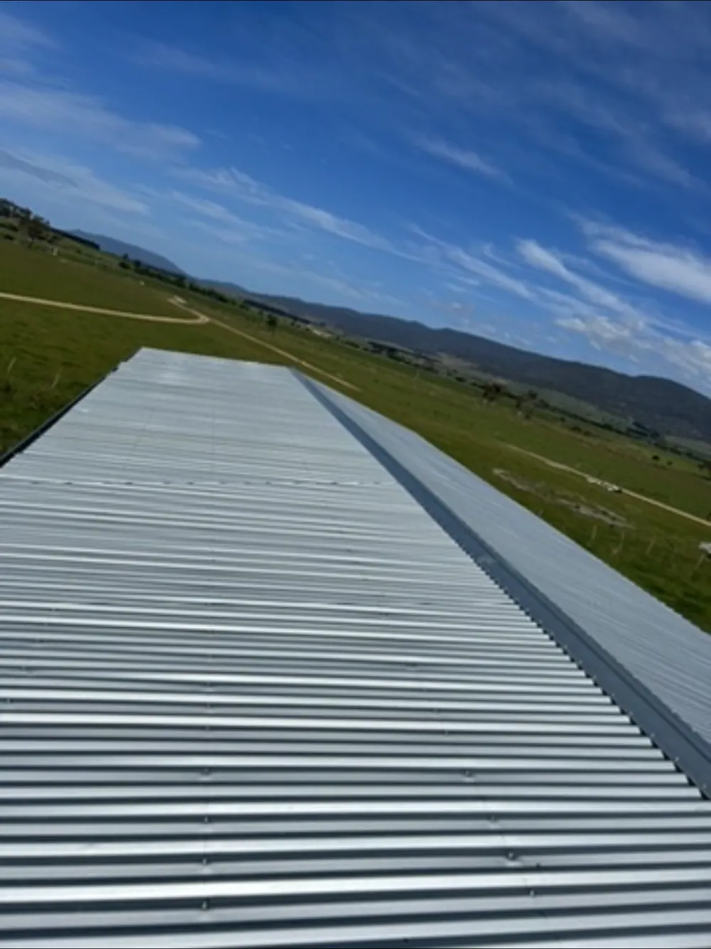 Metal roof sheets extending towards open fields and hills