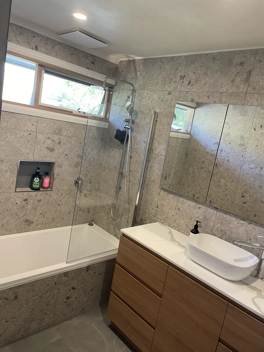 Bathroom with a bath, timber vanity, stone-look tiles and mirrored cabinet